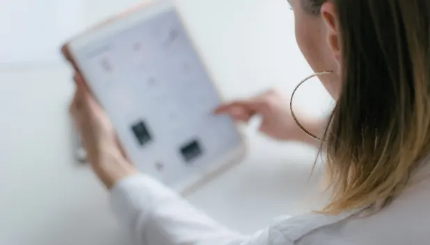 Photo d'ambiance : une personne consulte une application sur tablette, l'écran volontairement flou n'est pas lisible